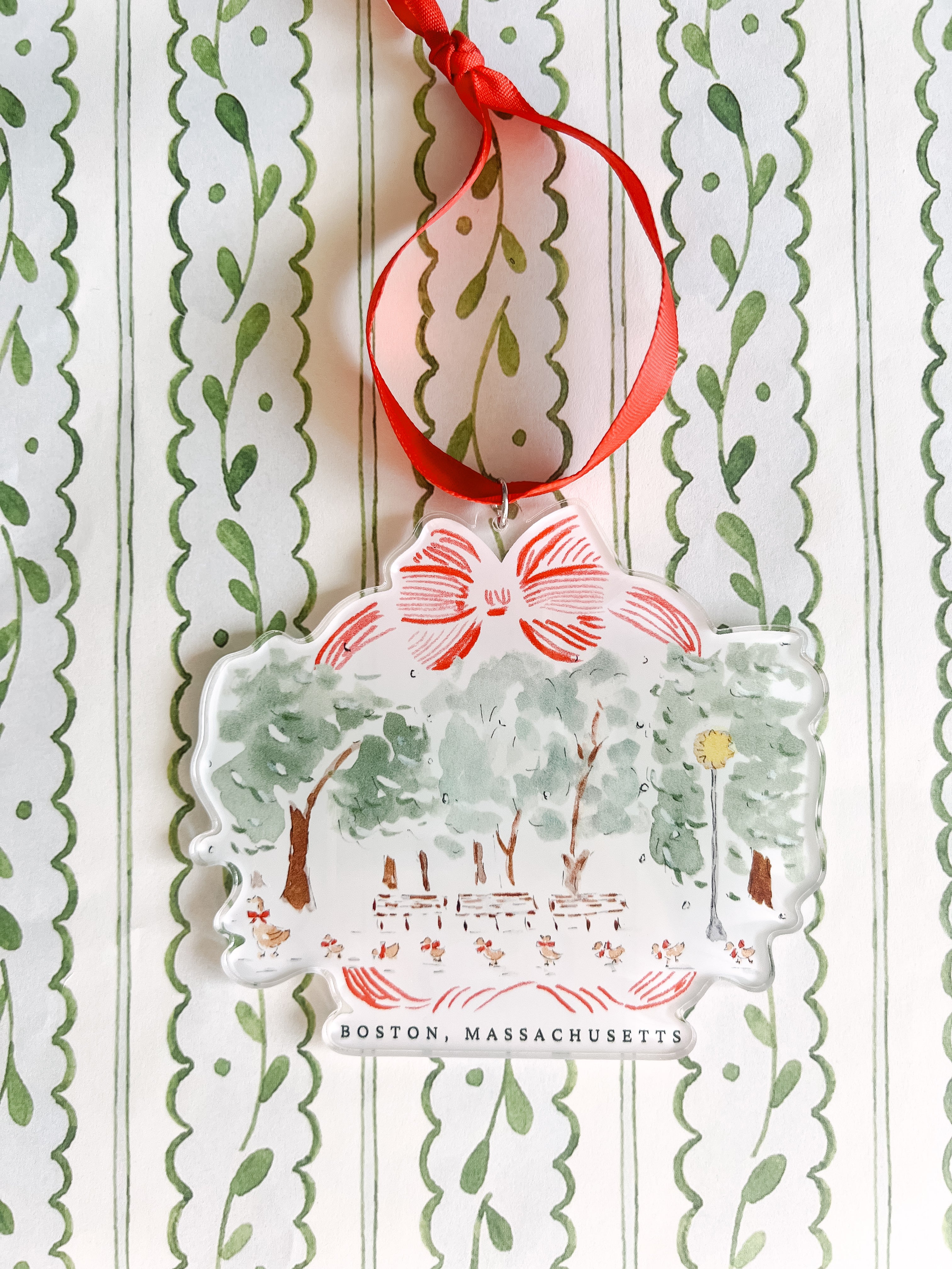 Acrylic ornament with a depiction of ducklings and a Christmas tree, featuring green, red, and beige colors, with 'Boston Massachusetts' written on it.
