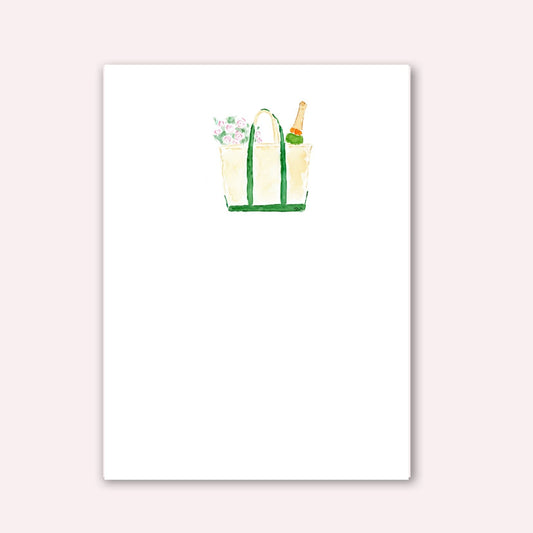 Notepad with tan boat and tote bag with green handles with flowers and champagne