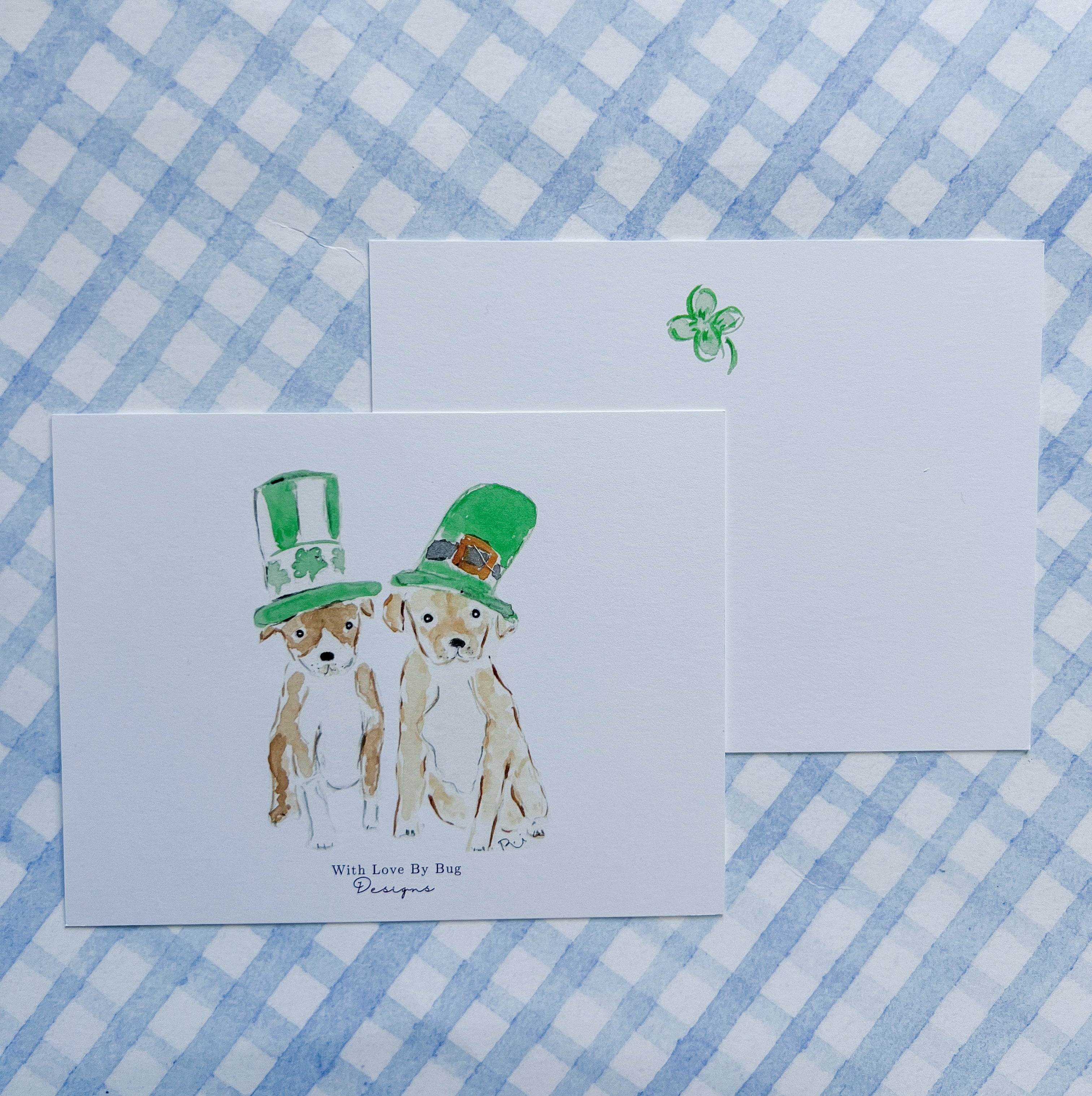 Two cards with illustrations of dogs wearing St. Patrick's Day hats on a blue and white checkered background.